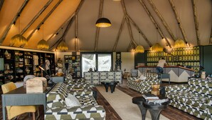 A tented accommodation with a bar area, seating arrangements, and a staircase. - Chobe River Camp (Ngoma)