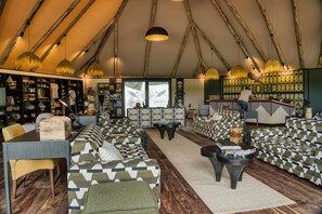 A tented accommodation with a bar area, seating arrangements, and a staircase. - Chobe River Camp (Ngoma)