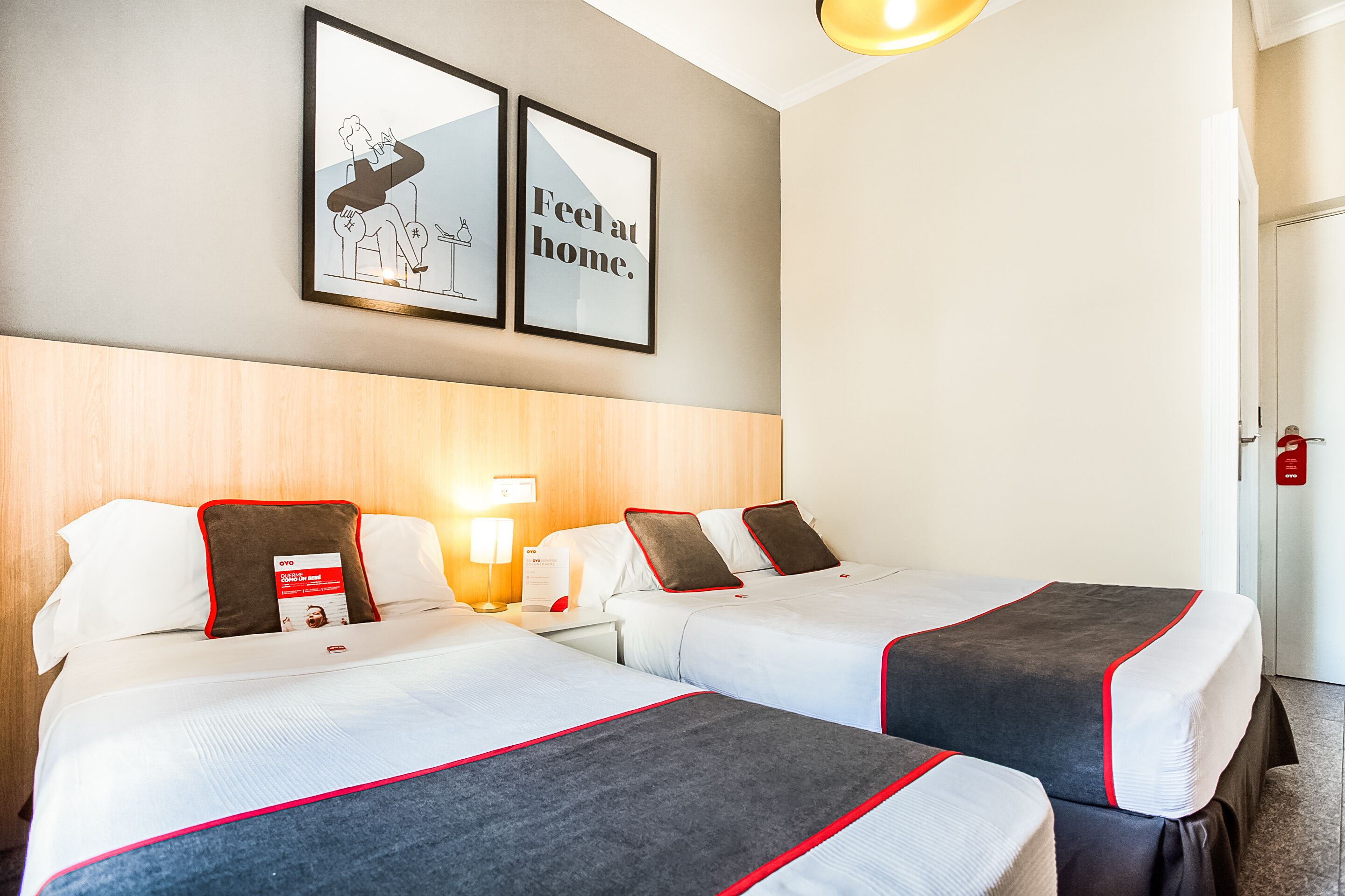 Une chambre d’hôtel avec deux lits, une tête de lit en bois, des œuvres d ’art encadrées au mur et une table de chevet avec une lampe.