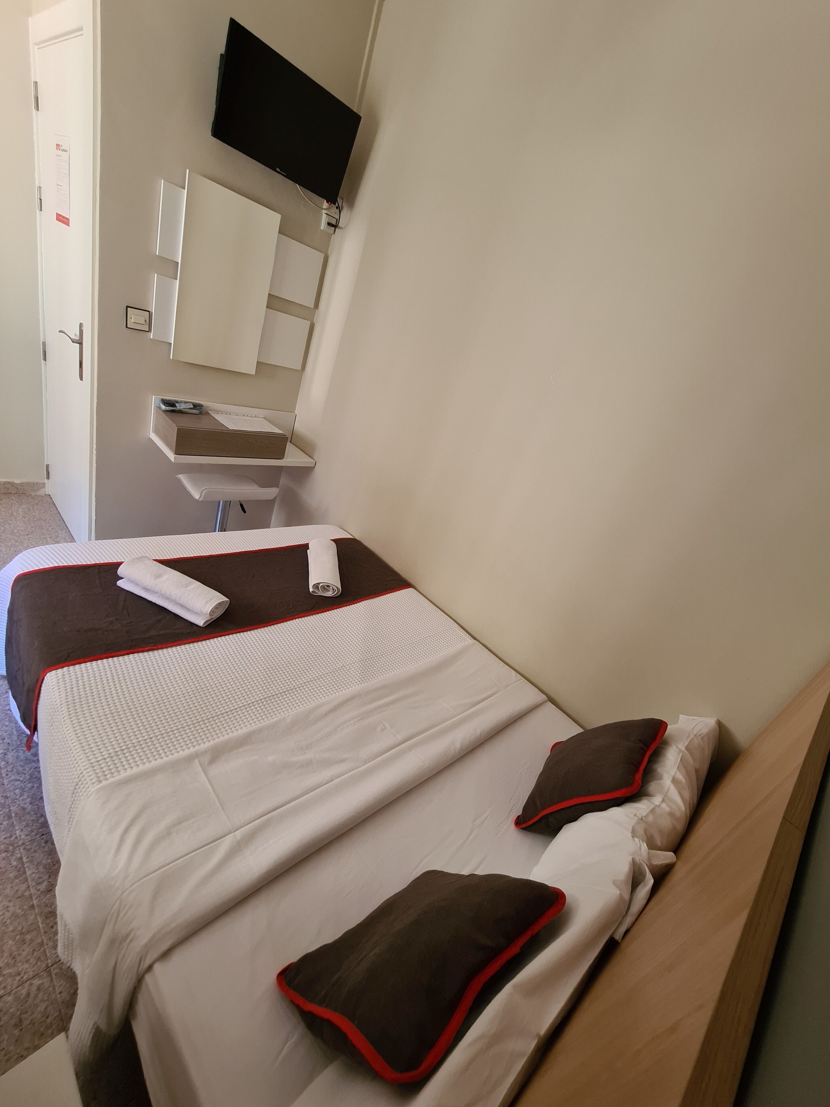 Een hotelkamer met een bed, een bureau, een stoel, een spiegel en een televisie.