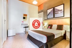 A hotel room with a bed, a desk, a chair, a mirror, and a sign indicating it is a certified sanitary room. - CH Las Murallas (Madrid)