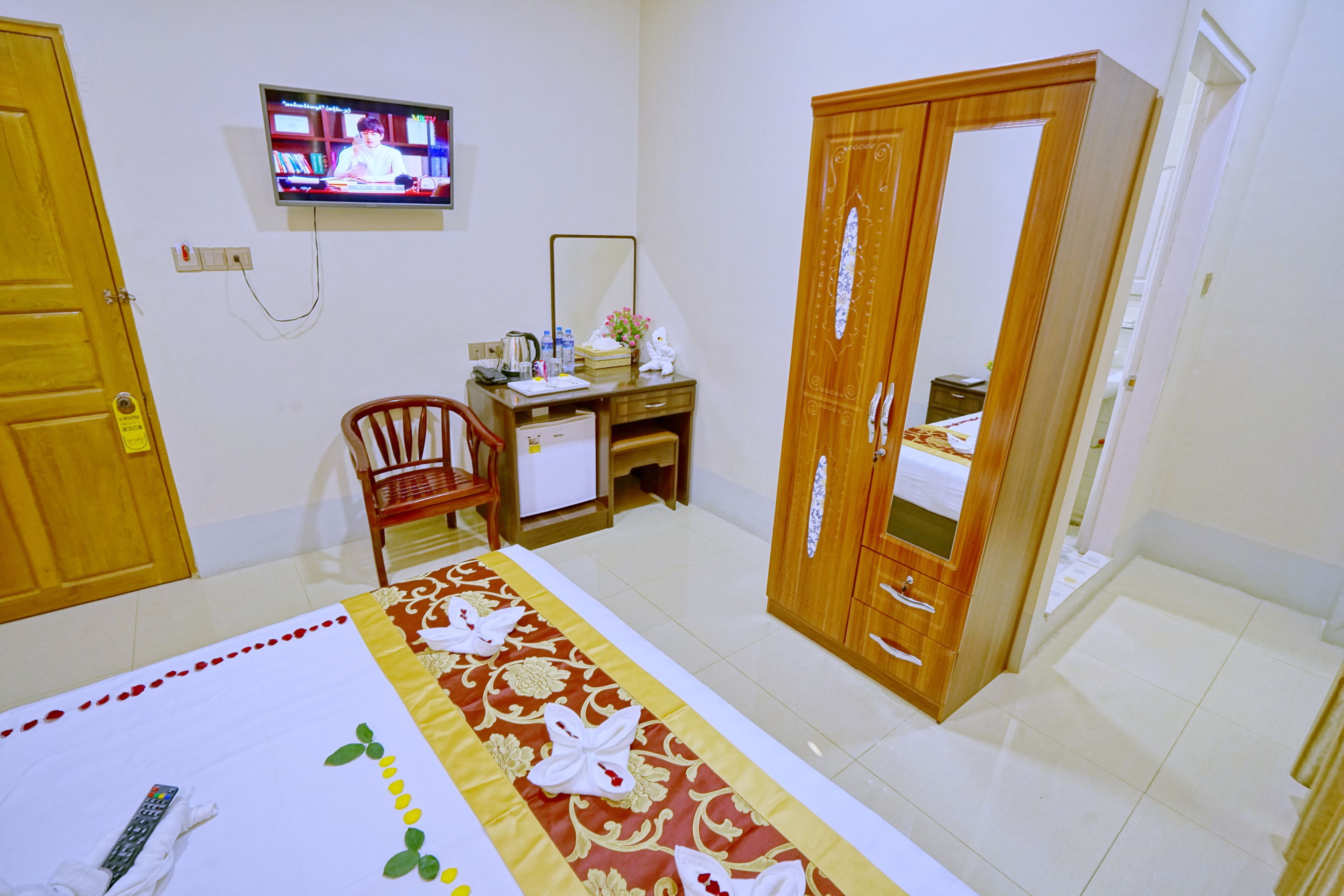 A hotel room with a bed, a desk, a chair, a television, and a wardrobe.