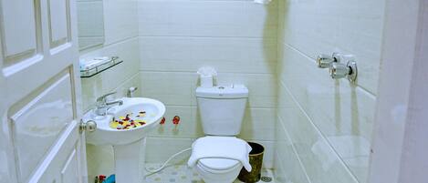 A small bathroom with a toilet, sink, and shower.