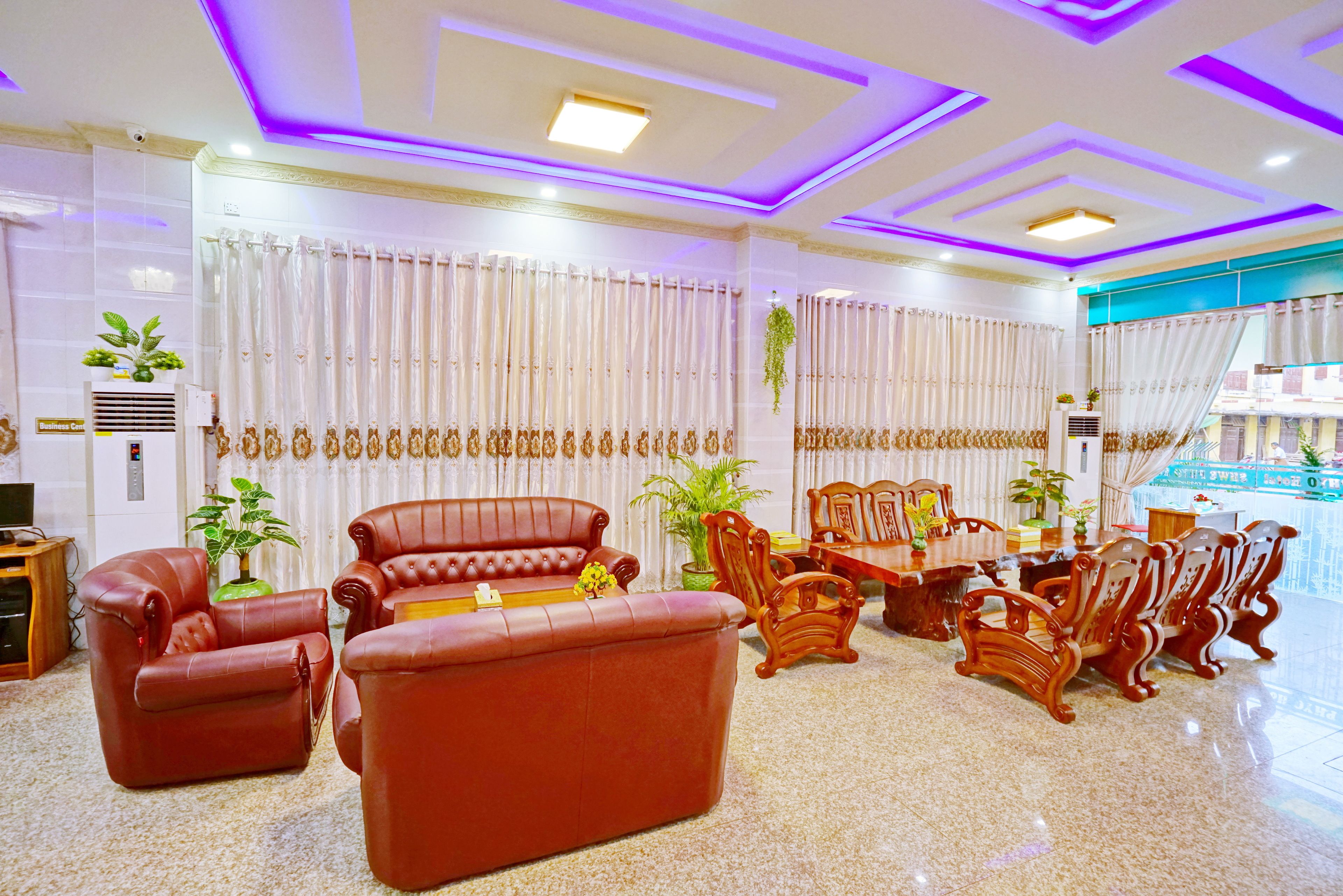 A spacious living area with leather sofas, wooden chairs, and a dining table.