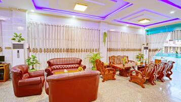 A spacious living area with leather sofas, wooden chairs, and a dining table.