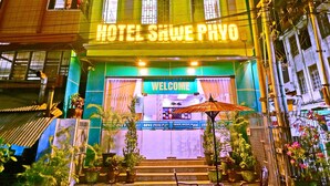 A multi-story building with a sign reading "HOTEL SHWE PHYO" and a "WELCOME" sign at the entrance. - Hotel Shwe Phyo (Mandalay)