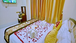 A hotel room with a neatly made bed, a television mounted on the wall, and a window with curtains. - Hotel Shwe Phyo (Mandalay)