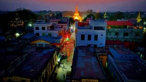 A cityscape at dusk with illuminated buildings and a prominent temple in the distance. - Hotel Shwe Phyo (Mandalay)