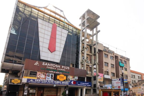 A building with a large sign for Santosh Plus Family Dhaba, featuring a prominent red arrow.