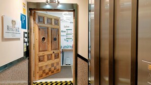 A hotel entrance with a wooden door, a reception desk, and a sign for 'ROYAL CRUZ'. - Hostal Royal Cruz (Madrid)