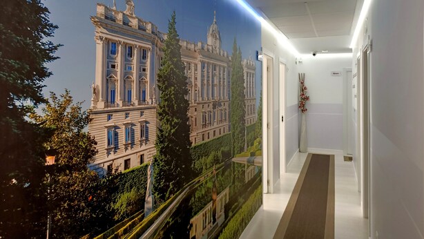 A hallway with a mural of a classical building, a number sign, and a modern light fixture. - Hostal Royal Cruz (Madrid)