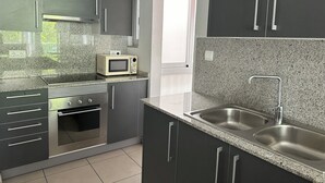 A modern kitchen with dark cabinets, a microwave, an oven, and a stainless steel sink. - Voramar 2A - One Bedroom Apartment, Sleeps 4 (Roses)
