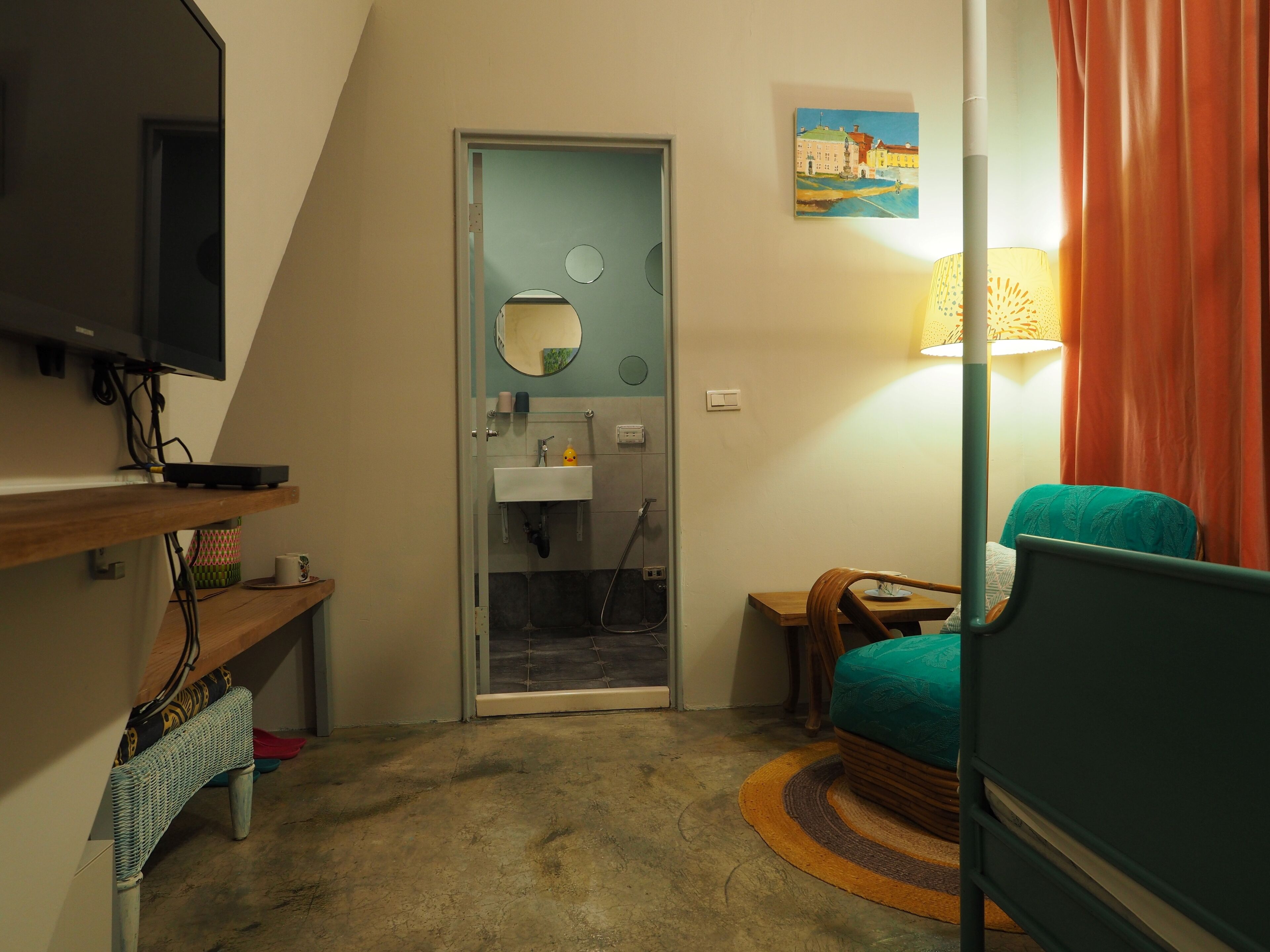 A compact room with a television, a small sink, a chair, and a bed.