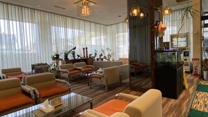 Un hall d’hôtel comprenant des espaces aménagés avec des sièges, un comptoir d’accueil et un aquarium.