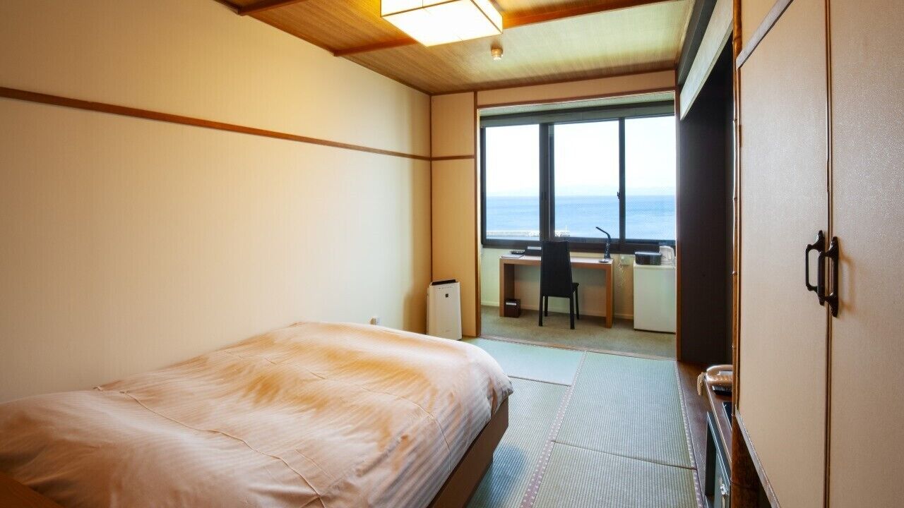 Una habitación con cama, escritorio y vista al mar.