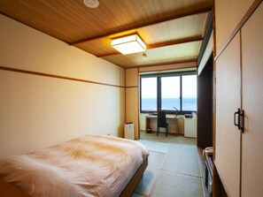 A hotel room with a bed, a desk, and a view of the sea. - Ryokan Asamushi Onsen Hotel Akitaya (Aomori)