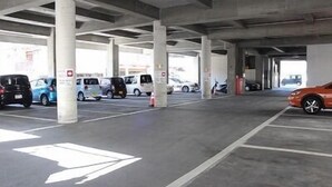 A parking garage with concrete pillars, marked parking spaces, and vehicles parked.