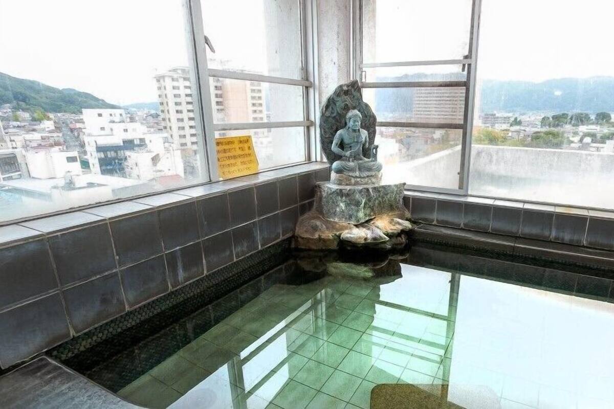 Ein Zimmer mit einem großen Fenster, einer Statue und einem gefliesten Boden.