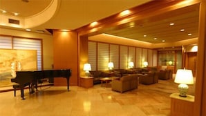A spacious lobby with a grand piano, comfortable seating, and warm lighting.