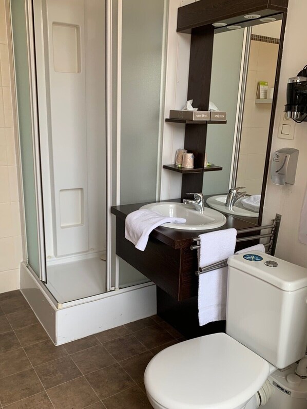 Baño con ducha, lavamanos, inodoro y espejo.
