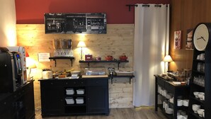 A hotel lobby with a wooden floor, a coffee station, a clock, and a buffet area. - Hotel du Midi (Annonay)