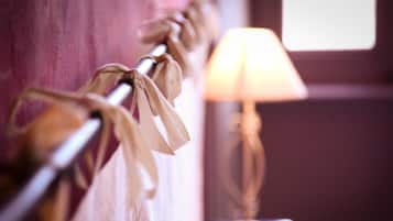 A close-up of a curtain tied with a ribbon, a lamp, and a window in the background.