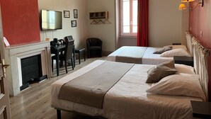 A hotel room with two beds, a desk with a chair, a television, and a fireplace. - Hotel du Midi (Annonay)