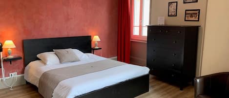 A bedroom with a black bed, two bedside lamps, a dresser, and a chair.
