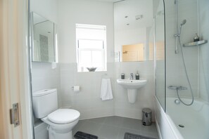 A modern bathroom with a toilet, sink, and shower. - Station Suites (Watford)