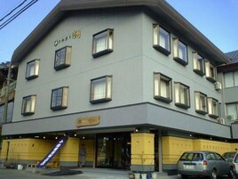 Um hotel com vários andares, fachada plana, diversas janelas e entrada visível.