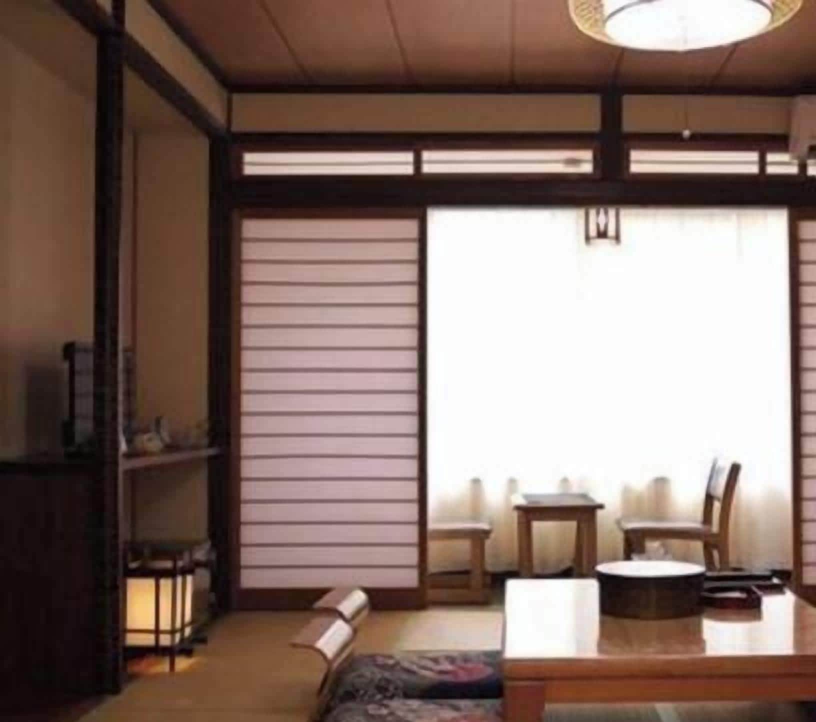 A traditional Japanese-style room with tatami flooring, a low table with chairs, and a sliding door.