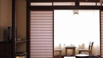 A traditional Japanese-style room with tatami flooring, a low table with chairs, and a sliding door.