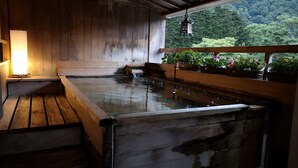 Un onsen japonés tradicional con bancos de madera y una pequeña fuente termal.