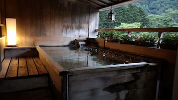 A traditional Japanese onsen with wooden benches and a small hot spring.