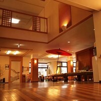 Interior espaçoso com teto alto, piso de madeira e uma grande estrutura em forma de guarda-chuva vermelha.
