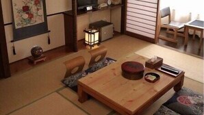 Et traditionelt japansk værelse med tatamimåtter, et lavt bord og et fjernsyn.