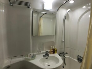 Un baño con lavamanos, espejo, ducha y artículos de aseo.