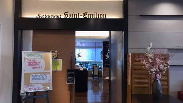 The entrance to Restaurant Saint-Emilion with a signboard and a vase of flowers on the right.