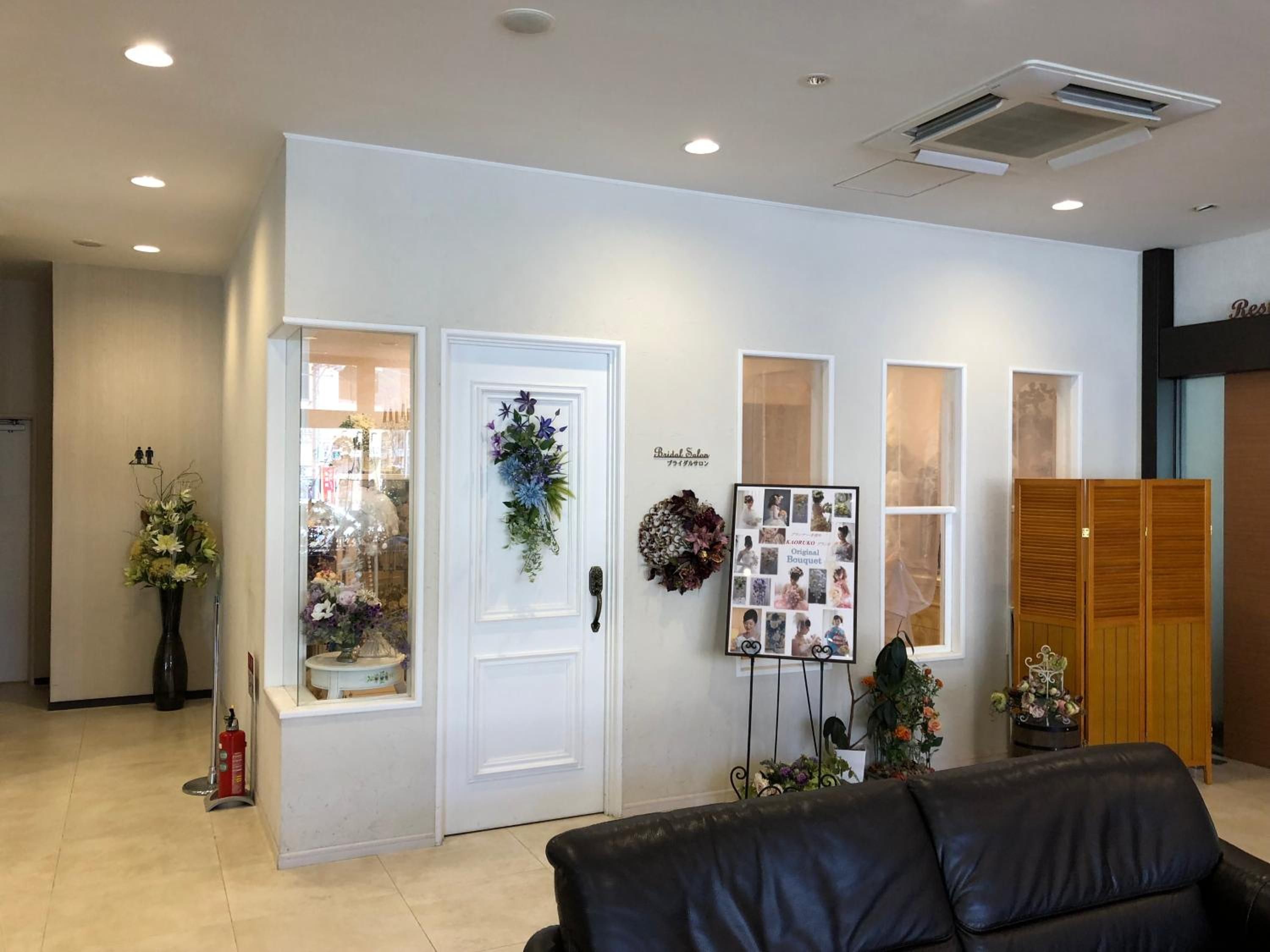 Una zona de recepción con una puerta blanca, un tablón de anuncios con fotografías y un sofá de cuero negro.