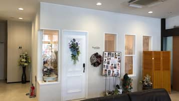 Una zona de recepción con una puerta blanca, un tablón de anuncios con fotografías y un sofá de cuero negro.