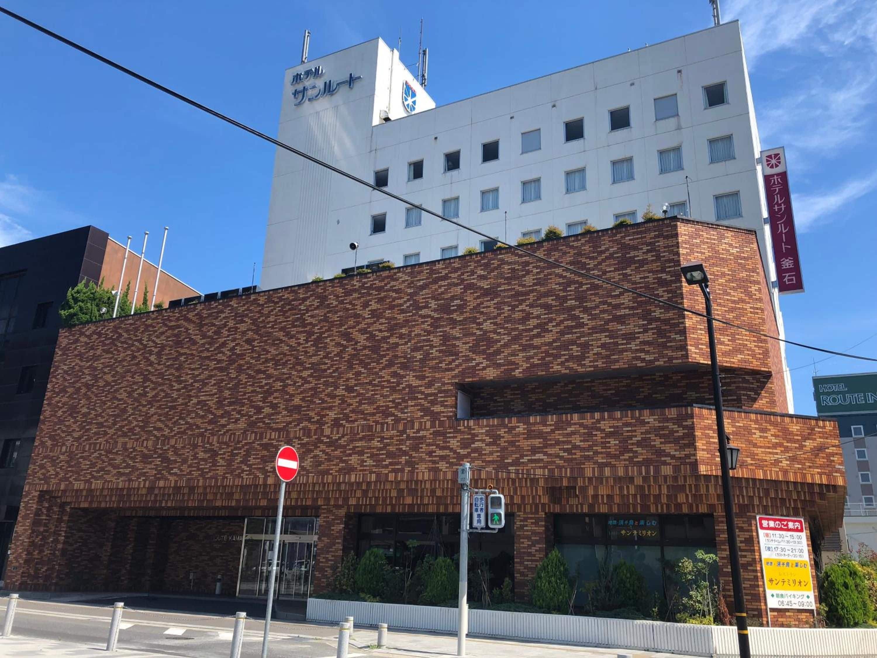 A hotel with a modern brick facade, a no entry sign, and a pedestrian crossing sign.