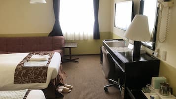 A hotel room with two beds, a desk, a chair, a desk lamp, a telephone, and a window with curtains.