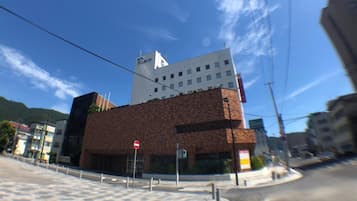 A building with a modern architectural design, featuring a prominent white and brown facade, and a visible traffic light.