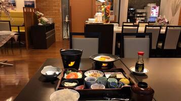 A dining table set with a hot pot, various dishes, and a bottle of soy sauce.