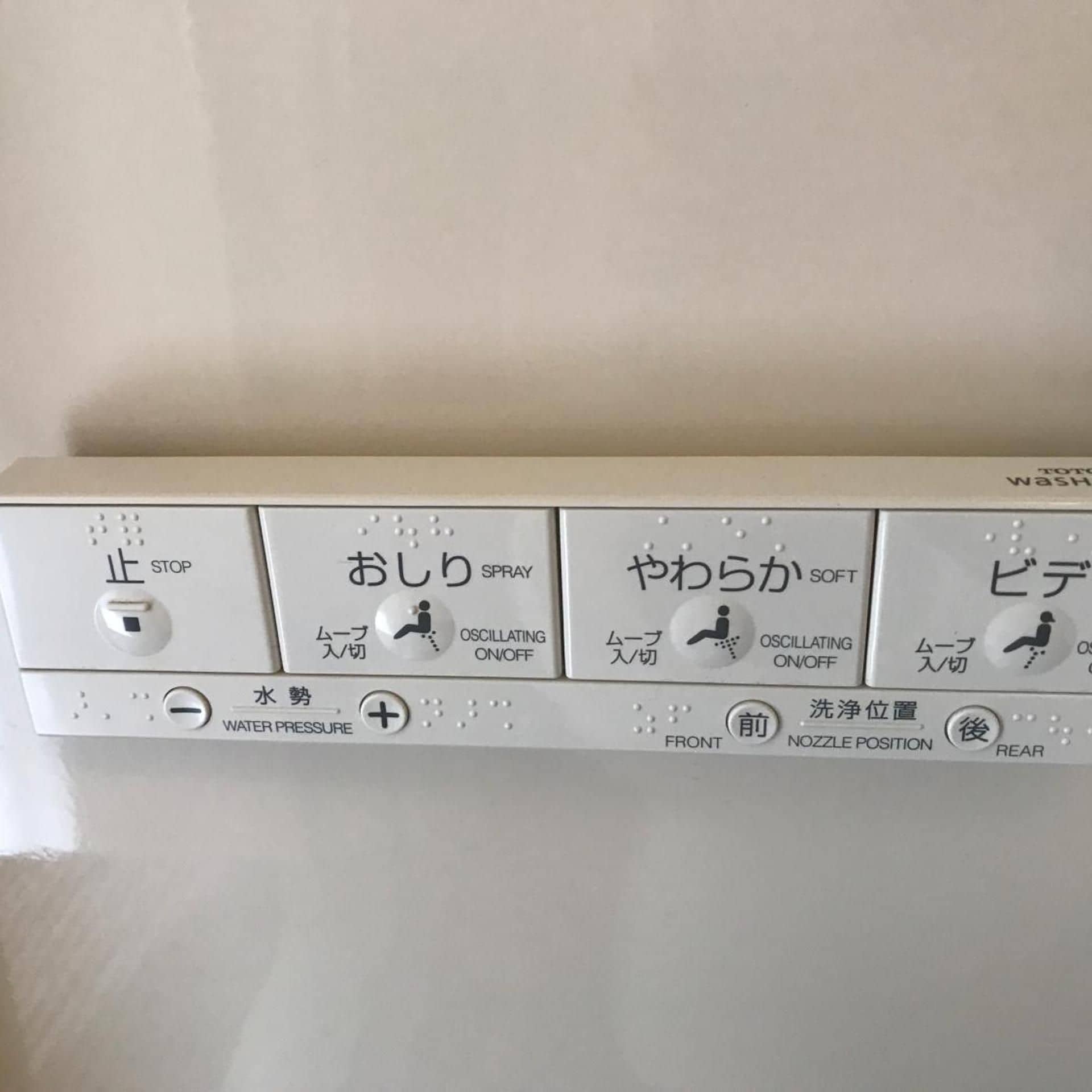 A control panel with Japanese labels for stop, spray, soft, and rear functions, along with water pressure and nozzle position controls.