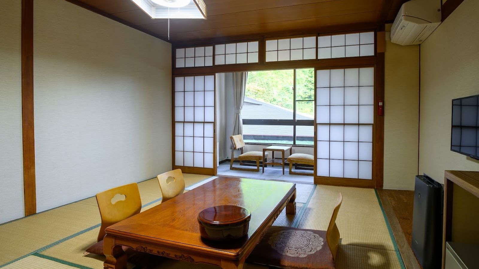 Een traditionele Japanse kamer met tatami vloerbedekking, een houten tafel en verschuifbare shoji deuren.