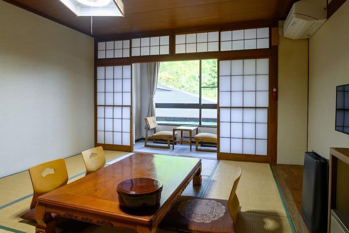 Une pièce de style japonais traditionnel, avec un sol recouvert de tatamis, une table en bois et des portes coulissantes en papier de riz (shoji).