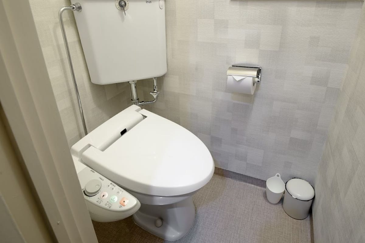 Une salle de bain moderne équipée de toilettes, d’un bidet et de deux poubelles.