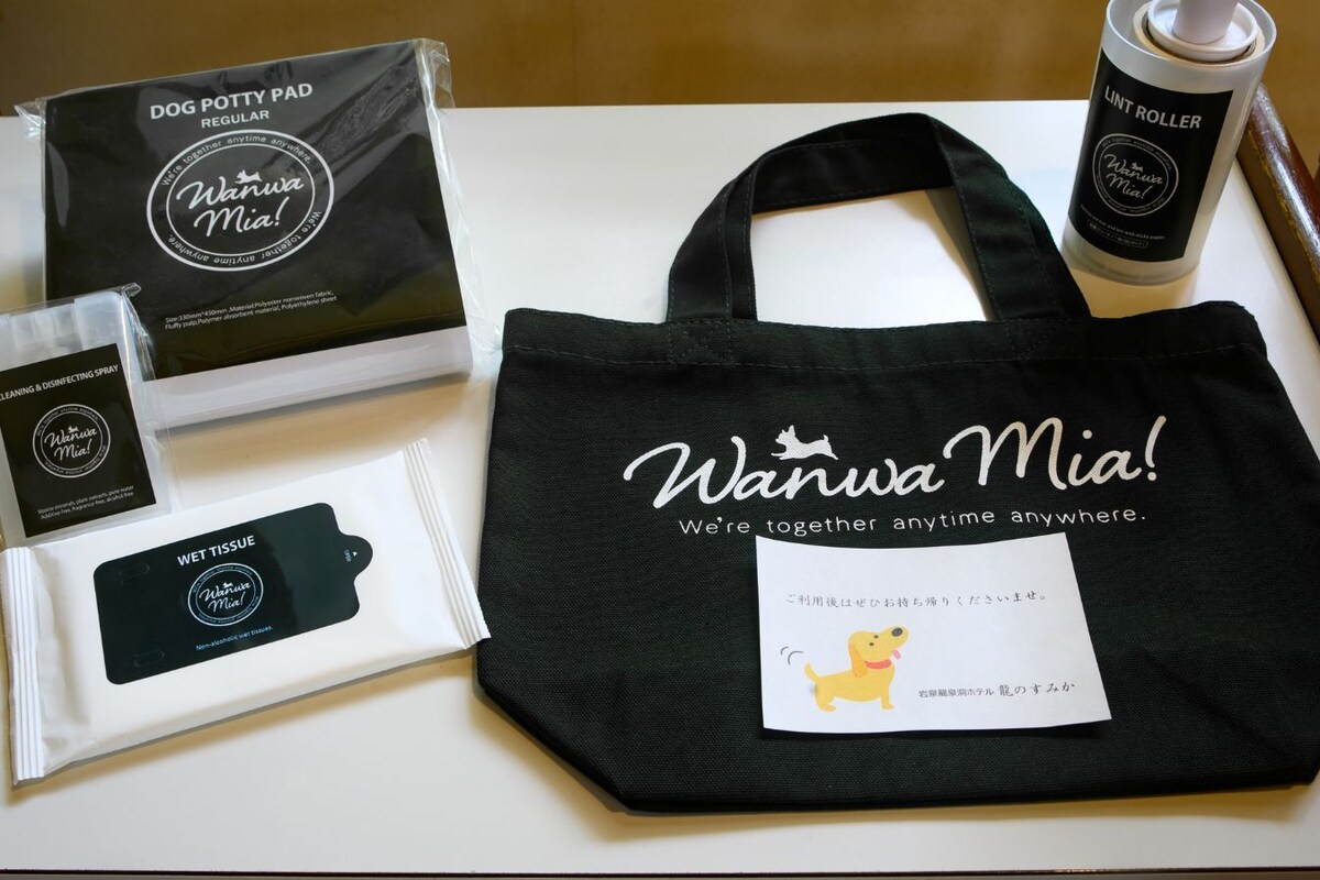 A dog potty pad, a cleaning spray, a wet tissue, and a black tote bag with the text 'Wanwa Mia!' and a dog illustration.