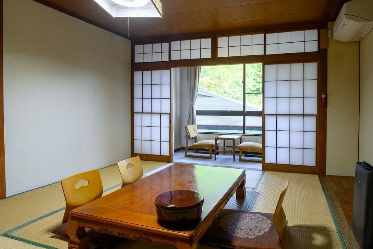 A traditional Japanese room with tatami flooring, a wooden table, and sliding shoji doors.